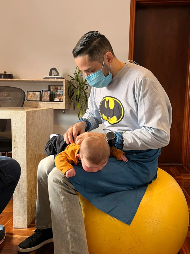 Sessão de osteopatia pediátrica com o bebê apoiado no colo do terapeuta